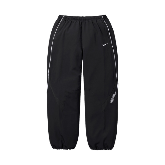 Supreme Nike Track Pant SS25 v čiernom prevedení - pohľad spredu. Výrazné sú voľný strih, elastický pás a charakteristické logo Nike Swoosh na pravej nohavici. Tepláky majú moderný oversized look s elastickými manžetami v dolnej časti.